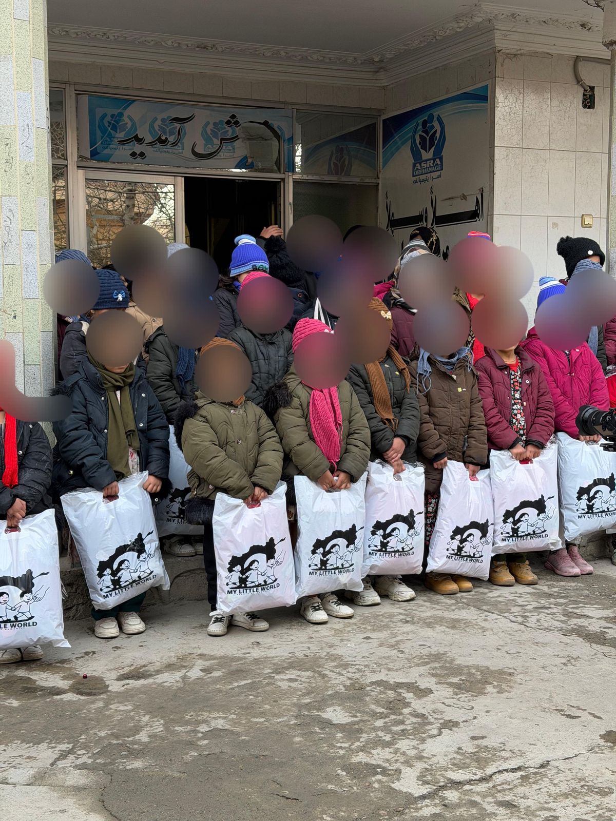 Children holding relief bags outside a partner orphanage